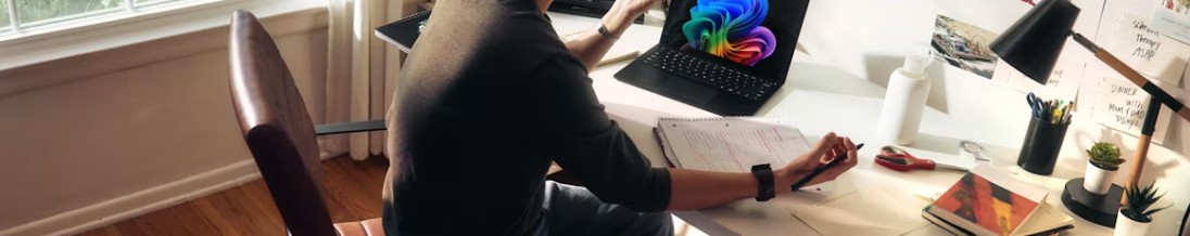 Person som sitter vid ett skrivbord med en laptop och ett block